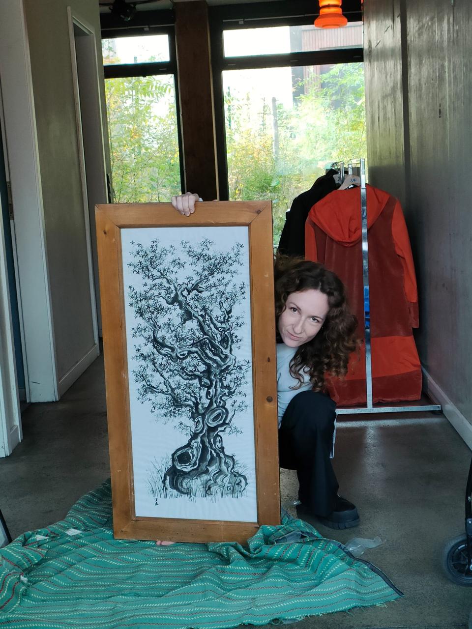 Coline Hercouët neben einer gerahmten Tuschezeichnung eines Baums